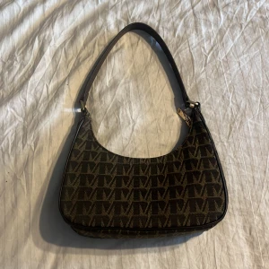 Svart/brun handväska  - Knappt använd axelväska i gott skick från Mango, passar bra till telefon och nödvändigheter om man ska ut på stan eller liknande. ONE SIZE. Den har dragkedja och en innerficka även med dragkedja 