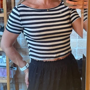 Randig croppad topp från H&M - Säljer en svartvit randig croppad topp från H&M. Toppen har korta ärmar, rund halsringning och är ribbad i materialet. Perfekt för dig som gillar en enkel men snygg stil med lite edge.