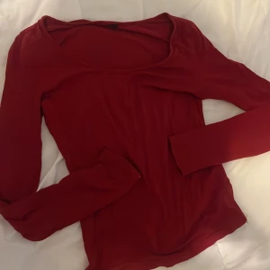 Röd långärmad topp med rund hals - En enkel och snygg röd långärmad topp med rundad halsringning. Modellen är figurnära och passar perfekt till jeans eller kjol. Tunt och mjukt material som känns skönt mot huden. Perfekt för lager-på-lager under hösten eller våren. Strykas kan fixas innan toppen skickas! :)