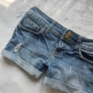 Lowwaist korta vintage shorts - Vintage lowwaist jeansshorts. Dom är som nya i skicket då dom är använda extremt sparsamt! Snygga fickor, samma stuk som Missme och true religion. Jättefin ”randig” tvätt. Kan skicka inom 1-2 dgr. Hör av er för frågor eller bilder❤️
