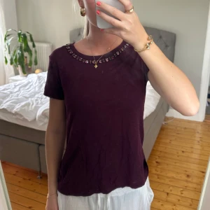 Vinröd t-shirt med pärldetaljer - T-shirt med detalj upptill