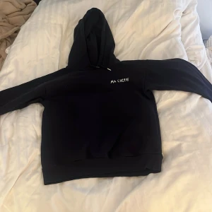 Svart hoodie med silvertryck Ma Chérie - Marinblå hoodie med huva och snörning, dekorerad med vitfärgade tryck 'MA CHÉRIE' och hjärtan både fram och bak. Mjuk och skön, perfekt för dig som gillar en chill och snygg streetstil.i storlek 146/152 men passa mig med storlek 158