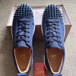 Marinblå och Vita Christian Louboutin skor - Snygga marinblå och vita skor från Christian Louboutin i mocka med klassisk röd sula. Skorna har snörning och rund tå, samt vita kanter på sulan. Perfekt för dig som vill sticka ut med exklusiv streetstyle. 