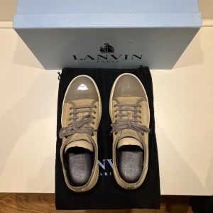 Mockaskor från Lanvin i beige och grå - Snygga Lanvins i beige mocka, grå lackad toecap och grå snörning. Perfekta skor som kan bäras året runt. Sparsamt använda men med små repor på hälkragen. Storlek UK 8 = EU 42,5 - 43. Kommer med originalkartong och dustbag. Skriv vid minsta fundering!🙌