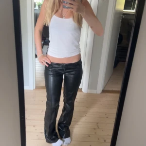 Svarta låga skinnbyxor Gina Tricot - Säljer ett par svarta låga byxor i skinnimitation från Gina Tricot. 