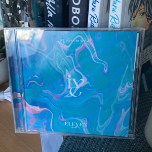 IVE JAPAN 1st SINGLE ELEVEN - Färgstark och stilren japansk singel från populära K-popgruppen IVE. Innehåller låtarna 'ELEVEN' och 'Queen of Hearts'. Perfekt för dig som älskar musik, samlar på K-pop eller vill ha snygga photocard i din samling!