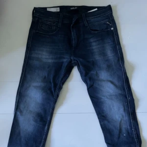 Replay jeans mörkblå, midja 31/32 - Snygga mörkblå jeans från Replay med klassisk femficksdesign och diskreta slitningar. Jeansen har raka ben och normal passform, perfekta för dig som gillar stilrena och bekväma byxor. Materialet är slitstarkt denim och färgen är djupblå.