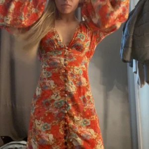 Röd blommig kortklänning från Adoore - Superfin röd/orange kortklänning från Adoore🥰. Aldrig använd, endast provad. Har däremot klippt lapparna. Säljer pga att figursydda passformen är lite för tight för min bekvämlighet, så den kommer aldrig till användning!! Vad jag ser så verkar den inte säljas längre på hemsidan🤞🏼🤞🏼