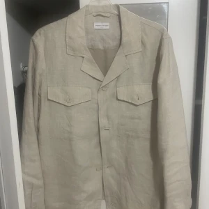 Beige overshirt från These Glory Days - Stilren beige overshirt från These Glory Days i linne. Bara använd 2 gångwe så helt i nyskick. Köpt för 999
