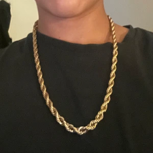 Guldfärgat tvinnat halsband - Säljer ett snyggt guldfärgat halsband med tvinnad kedja. Som är stål och går att bada dusha osv. Längden är cirka 30cm och halsbandet har en klassisk låsning. Perfekt accessoar för att lyfta din stil med en clean och trendig look.