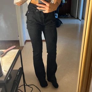Svarta True Religion bootcut jeans - Svarta jeans från True Religion, modell Becca Mid Rise Bootcut. Snygg bootcut-passform med råa kanter nertill och ikoniska bakfickor med kontrastsömmar och stora knappar. Jeansen är i stretchig bomull och har klassisk femficksdesign.