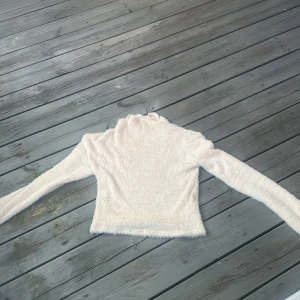 Vit fluffig polotröja Gina Tricot - Supermjuk och fluffig vit polotröja från Gina Tricot i storlek S. Tröjan har lång ärm och hög krage, perfekt för kalla dagar. Tillverkad i 100% polyamid för en riktigt cozy känsla. Enkel att matcha med jeans eller kjol för en chill look.