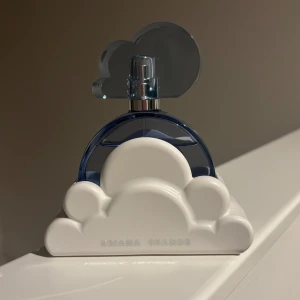Ariana Grande Cloud parfym - Superfin parfym från Ariana Grande i modellen Cloud. Flaskan är blå och genomskinlig med ett unikt molnformat vitt ställ och ett blått moln som lock. Perfekt som statement på sminkbordet och doftar magiskt sött och fräscht.