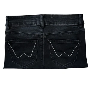Svart mini jeanskjol med snygga fickor - Cool svart jeanskjol med klassiska fickor bak och vit kontrastsöm i W-form. Kjolen är kort och storlek XS. Även i bra skick och inga tecken på användning. Perfekt till semestern!!