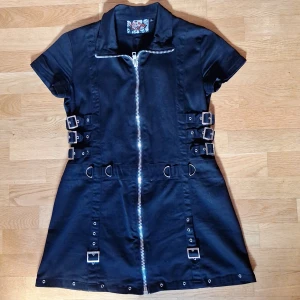 Svart kort klänning Living Dead Souls - Svart kort klänning från Living Dead Souls med metall detaljer som dragkedja, spännen och öljetter. 