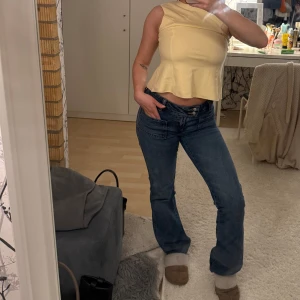 Lågmidjade blå bootcut jeans - Säljer ett par blå jeans med låg midja och bootcut-ben. Jeansen har dubbla knappar i midjan, stora framfickor och klassiska bakfickor. Lågmidjade oxh trendiga, aldrig använt dessa! Storlek full length xs 🌸
