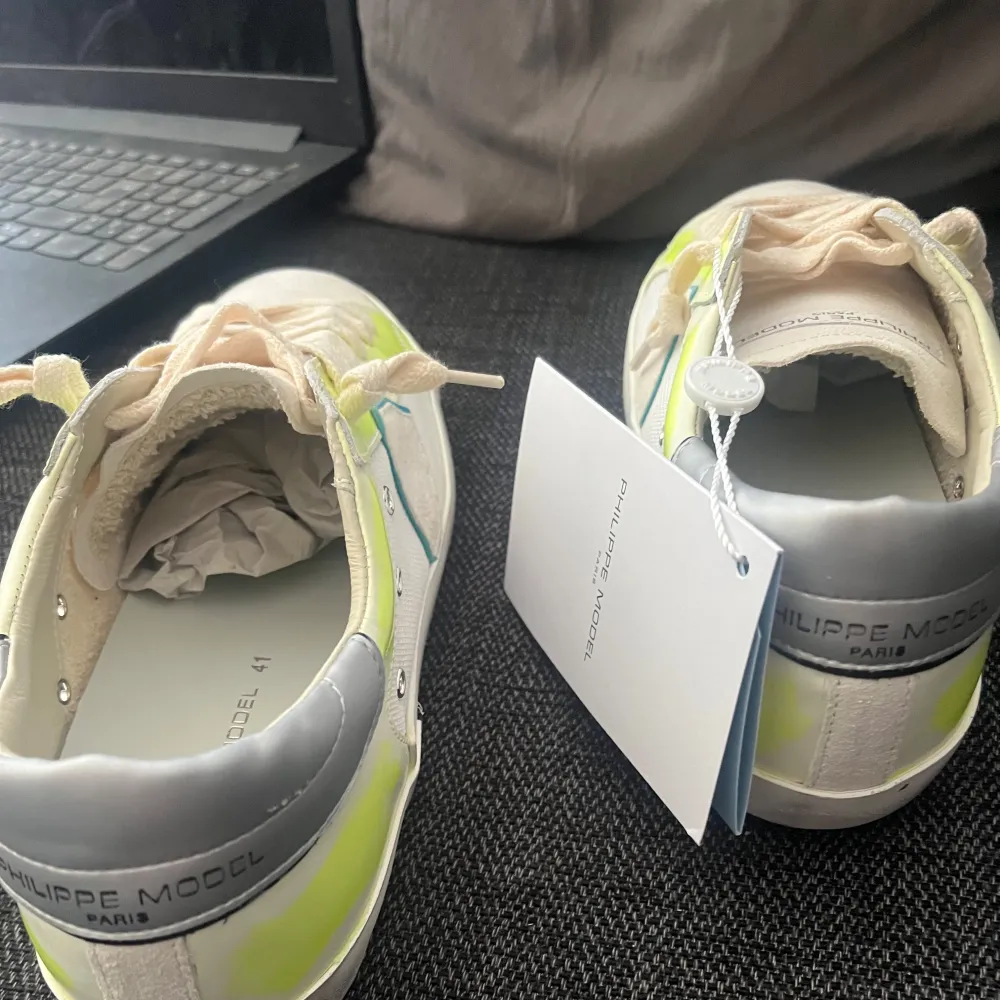 Snygga Philippe Model sneakers i vitt med neongula detaljer. Skorna har en rund tå och snörning framtill. Perfekta för att ge din outfit en färgklick. Tillverkade i en kombination av skinn och syntetmaterial. Pris kan diskuteras . Kengät.