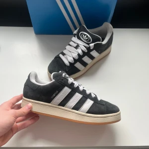 Svarta Adidas Campus sneakers - Snygga svarta Adidas Campus sneakers med vita detaljer och klassiska tre ränder. De är i perfekt skick. Fråga om du har några frågor