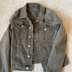 Grön jeansjacka från Sincerely Love - Snygg grön jeansjacka från Sincerely Love i storlek S. Jackan har en klassisk design med knappar framtill och två bröstfickor med lock. Perfekt för en casual look.