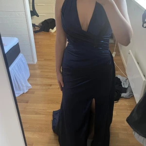 Mörkblå balklänning  - En väldigt elegant mörkblå balklänning i satin. Klänningen är halterneck med öppen rygg, har en jättefin slit på högra benet och ett fint släp. Klänningen är köpt på flormiss, den är endast testad aldrig använd och säljs bara för att jag köpte 2 st och tycker om den andra mer. Jag är en Medium i vanliga fall, på hemsidan inföll jag i måtten för storlek 40 och det är den klänningen är i. Om ni vill ha specifika mått eller fler bilder får ni jättegärna skriva❤️jag betalade 1500 för klänning och fra