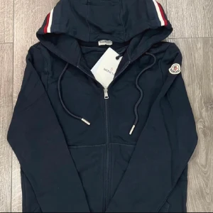 Moncler zip hoodie - Säljee min moncler kofta då den är som ny nästan. Inga konstigheter med den. Tillkommer med tags, påse, qr kod samt NFC scan. Hör gärna av dig vid fler frågor!!