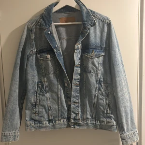 Ljusblå jeansjacka  - Snygg ljusblå jeansjacka  med klassisk design. Jackan har knappar framtill och två bröstfickor med lock. Perfekt för en avslappnad stil.