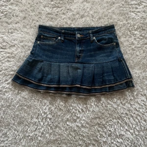 Jeanskjol med volang - En lågmidjad jeanskjol omsydd från ett par jeans Midjemått tvärsöver - 40 cm Längd - 34 cm
