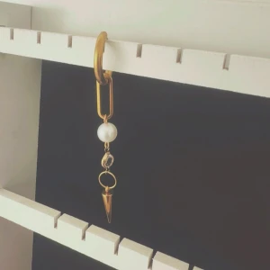 Guldörhänge med pärla och spetsig detalj - Elegant guldörhänge med en stor vit pärla och en spetsig hängande detalj. Perfekt för att ge en stilfull touch till din outfit.