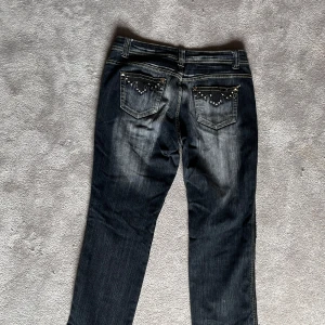 Mörkblå jeans med nitar från Miss O&V - Snygga mörkblå jeans med coola nitar på fram- och bakfickorna från Miss O&V. De har en klassisk femficksdesign och en knappgylf. Perfekta för en edgy look!