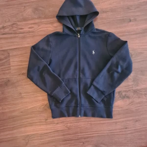 Mörkblå hoodie från Ralph Lauren - Säljer en snygg mörkblå hoodie från Ralph Lauren med dragkedja och det klassiska broderade logotypen på bröstet. Storlek xs, fint skick!