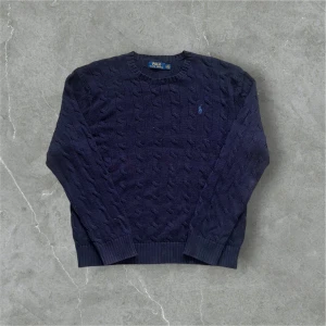 Mörkblå Kabelstickad från Polo Ralph Lauren - Säljer en snygg mörkblå stickad tröja från Polo Ralph Lauren med kabelstickat mönster. Den är i perfekt skick. Inga defekter. Fråga om du har frågor