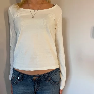 Vit långärmad topp - Säljer en stilren vit långärmad topp med rund halsringning. Perfekt för en enkel och avslappnad look. Passar bra till jeans eller kjol.