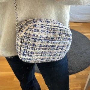 Väska från Beck Söndergaard - Säljer en snygg rutig axelväska från Beck Söndergaard. Väskan har en kedjerem och ett mönster i blått och vitt. Perfekt för att ge din outfit en stilfull touch. Oanvänd💞