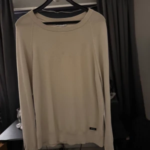 Beige tröja från Calvin Klein - Säljer en stilren beige tröja från Calvin Klein. Tröjan har en enkel design med långa ärmar och rund halsringning. Perfekt för en avslappnad och snygg look.