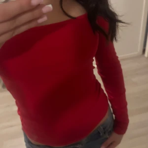 Röd långärmad topp - Snygg röd långärmad topp med en tight passform. Perfekt för att ge en färgklick till din outfit. Toppen har en enkel design som gör den lätt att matcha med olika stilar.