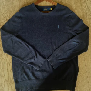 Mörkblå Polo Ralph Lauren tröja - Säljer en stilren mörkblå tröja från Polo Ralph Lauren med det klassiska logotypbroderiet i blått på bröstet. Tröjan har långa ärmar och en rund halsringning. Priset går att förhandla vid snabb affär!