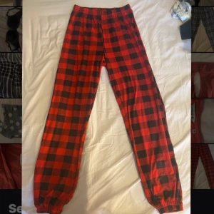 Röda och svarta rutiga byxor - Snygga och bekväma byxor i röd och svart rutig design. Perfekta för en avslappnad stil med elastisk midja och muddar vid bensluten. Passar bra för mysiga dagar hemma eller en avslappnad dag ute.