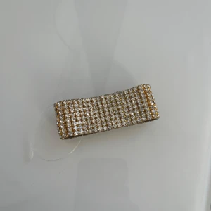 Glittrigt guldarmband - Snyggt guldarmband med flera rader av glittrande stenar. Perfekt för att ge en lyxig touch till din outfit. Armbandet har en flexibel design som gör det enkelt att ta på och av. Lite färg har släppts invändigt men inget som märks av på. Oanvänd. 