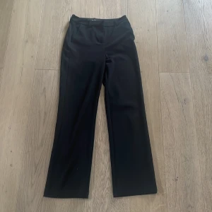 Svarta kostymbyxor - Snygga svarta kostymbyxor med normal midja och rak passform. Perfekta för en stilren look. Byxorna har en klassisk design som passar till många olika tillfällen.