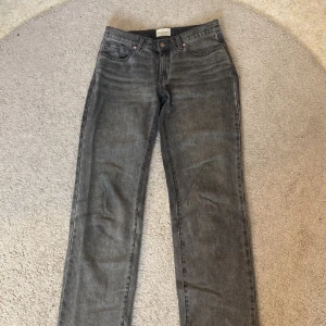 Grå Abrand ’99 Low Straight - Snygga grå jeans från Abrand Jeans med klassisk femficksdesign och raka ben. Jeansen har en mörkgrå tvätt och metallknapp med Abrand-logga. Perfekta för dig som gillar en enkel och stilren look.