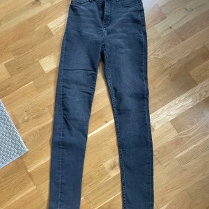 Svarta skinny jeans från Divided, stl 34 - Snygga svarta skinny jeans från Divided i storlek 34. Jeansen har klassisk femficksdesign, hög midja och smal passform hela vägen ner. Perfekta till sneakers eller boots och funkar året runt. Materialet är stretchigt för extra komfort.