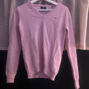 Ljusrosa stickad tröja från Gant - Superfin ljusrosa stickad tröja från Gant med v-ringning och diskret logga på bröstet. Använd en gång 
