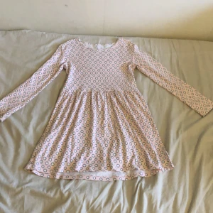 Ljusrosa prickig klänning från Livly - Supersöt ljusrosa klänning från Livly med vita och svarta prickar. Modellen är en kortklänning med lång ärm och rund hals. Mjuk och skön i bomull, perfekt för dig som gillar lekfulla och bekväma outfits. Pris kan diskuteras vid snabb affär.