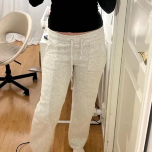 Grå mjukisbyxor med snörning M - Superbekväma ljusgrå mjukisbyxor från 157 med bred resår i midjan och snörning. Byxorna har raka ben, stora fickor fram och är gjorda i mjuk bomullsmix. Perfekta för chill eller träning.