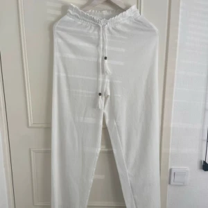 KÖP FRÅN MIN VINTED - Snygga och luftiga vita linnebyxor med resår i midjan och snörning framtill med dekorativa tofsar. Perfekta för varma dagar och en chill stil. Raka ben och avslappnad passform.