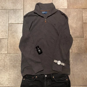 Ralph Lauren Quarter Zip Medium - Säljer en stilren grå Quarter Zip från Polo Ralph Lauren. Den har långa ärmar och en broderad logotyp på bröstet. Perfekt för en avslappnad och snygg look. Rikigt bra skick.