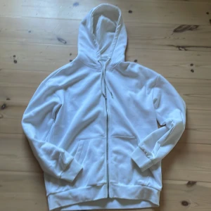 Vit hoodie med dragkedja från Pier One - Snygg vit hoodie från Pier One med dragkedja framtill och huva med snörning. Tröjan har två fickor på magen och är tillverkad i mjuk bomullsmix. Perfekt för en clean och avslappnad stil. Långärmad och med ribbade muddar för extra komfort.         Ny pris 349