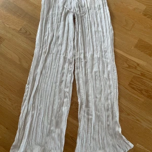 Vita vida byxor från H&M  - Snygga oanvända luftiga plisserade glansiga byxor från HM. 