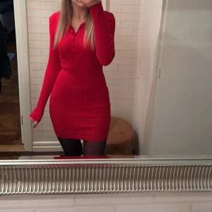 Röd ribbad klänning från Hera Collection -  röd ribbad kortklänning från Hera Collection med lång ärm och knappar vid halsringningen. Klänningen är stretchiga och fin i storlek S köpte i USA nå år sedan 