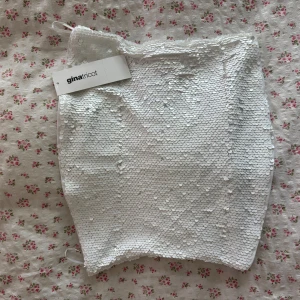 Vit paljett-tubtopp från Gina Tricot - Supersnygg vit tubtopp från Gina Tricot, helt täckt med glittrande paljetter. Aldrig använd, prislapp kvar. Nypris 299kr 